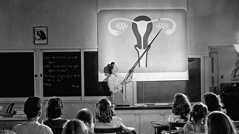 Hacia 1948 - Una docente marca con un puntero sobre un diagrama del sistema reproductor femenino proyectado sobre una pantalla en un aula de escuela secundaria. Escena de "Human Growth", un film educativo sobre educación sexual mostrado a estudiantes de las Oregon junior high schools empezando en 1948 --- Archivo fotográfico CORBIS